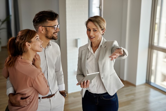 Renting an appartement in France with a real estate agent Happy real estate agent talking to a couple while showing them a new apart